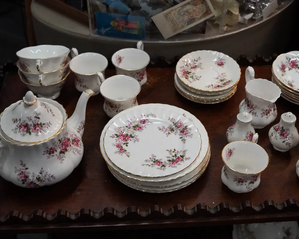Een theeservies met rozen op een donkere houten tafel