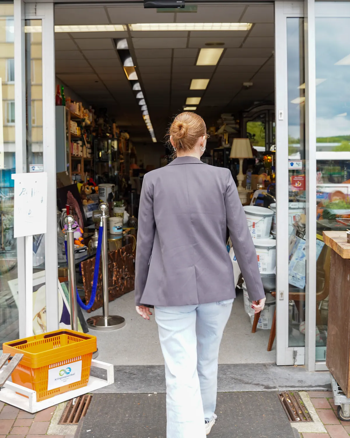 Een klant loopt met een gele winkelmand de winkel binnen