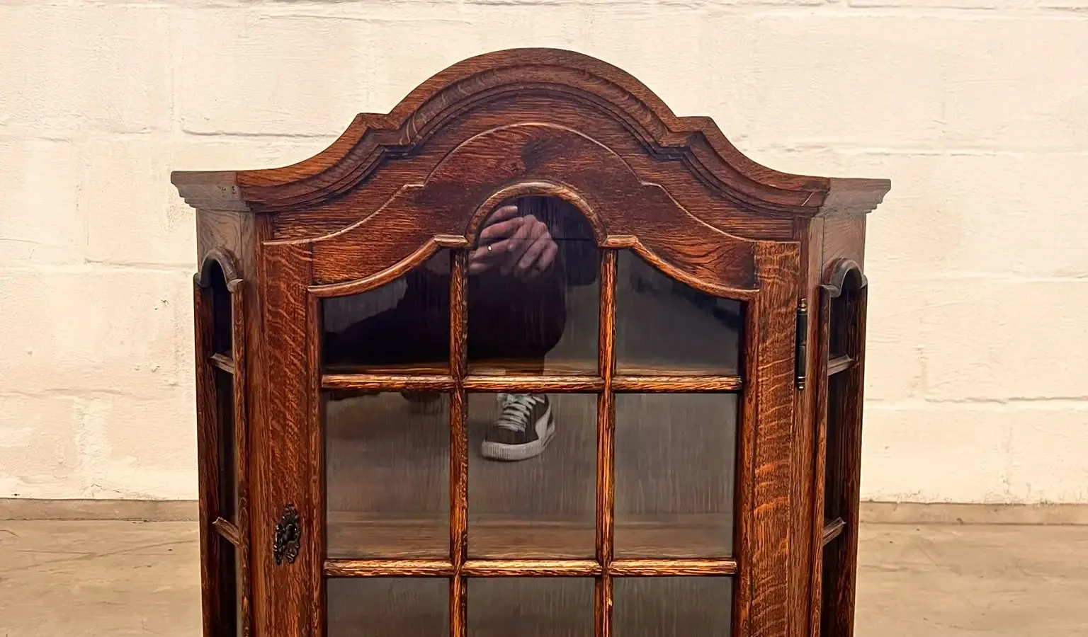 Een houten wandvitrine met glazen deur